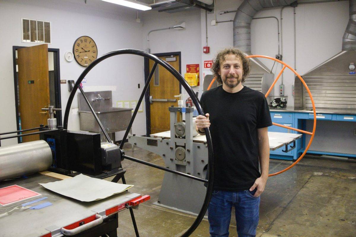 Jason Scuilla standing next to printing press in Willard Hall